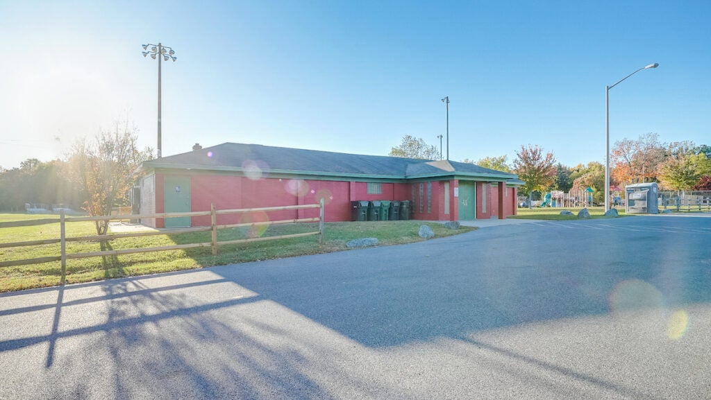 Exterior view of a single-story, red building with green doors and trim.