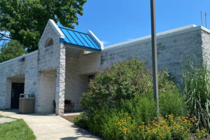 Exterior view of a white cinderblock building with a blue portico over the entrance.