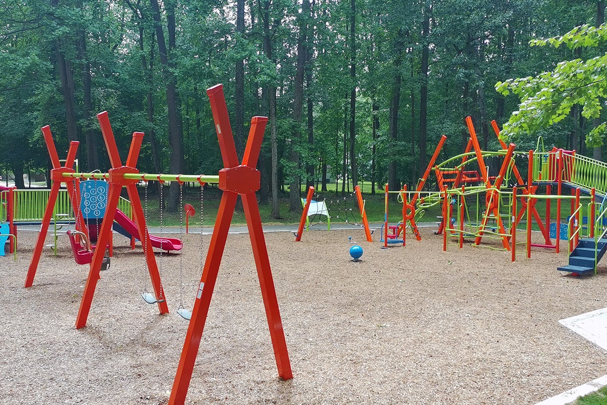 Wide view of the playground highlighting climbing structures, slides, swings, sensory play features, and open spaces for children of varying ages and abilities.