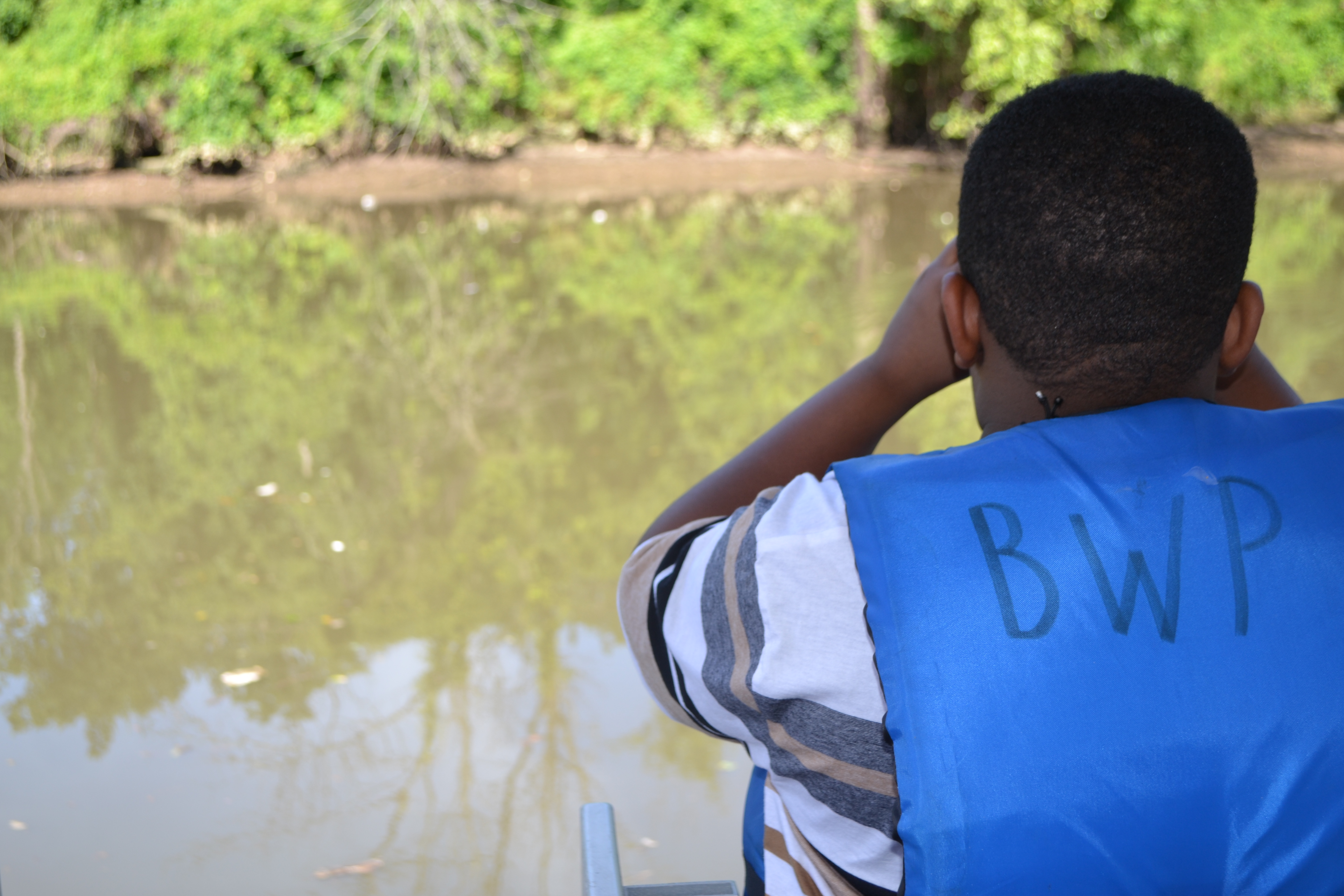 A student looks through binoculars at the river