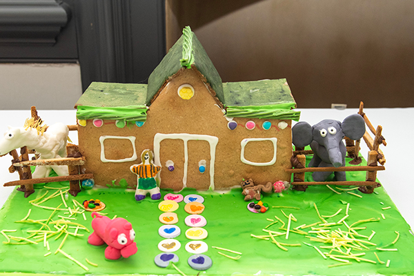 A rustic gingerbread barn, with a solid green gingerbread roof. It has frosting lined doors and windows