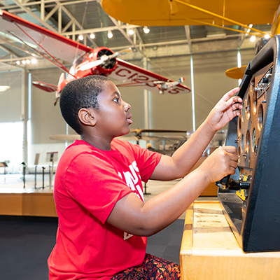 A child playing with an interactive exhibit at an aviation museum