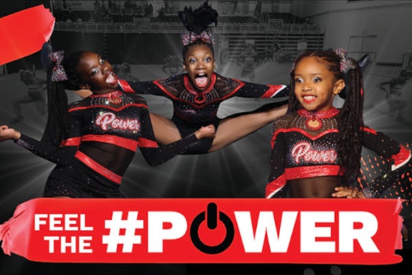 Three young girls doing cheerleading poses. They're wearing black and red outfits. The words 