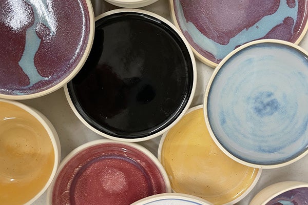 A collection of multi-colored glazed ceramic plates randomly placed in a composition.