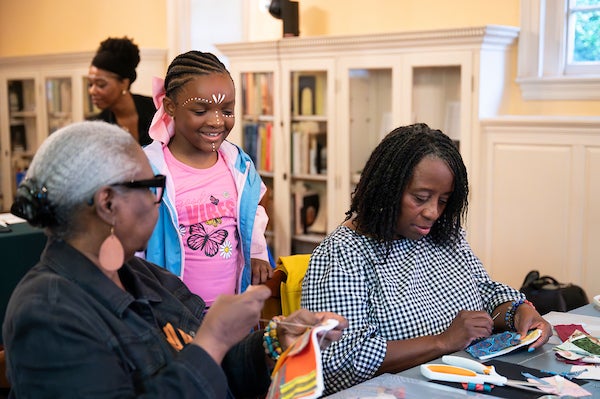Two women and a child sewing at a table