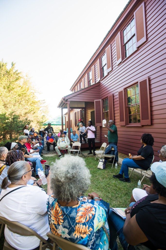 A group of people sitting in chairs outside of a burgundy house