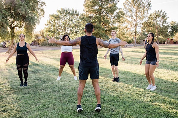 Five people exercising in a field of grass.