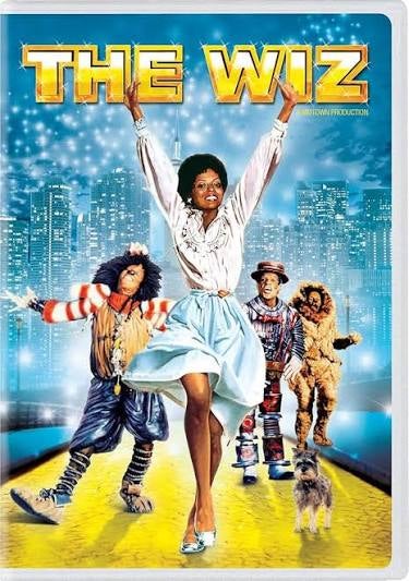 “The Wiz” poster: central dancer on yellow brick road, three companions behind, city skyline background, glowing gold title above.
