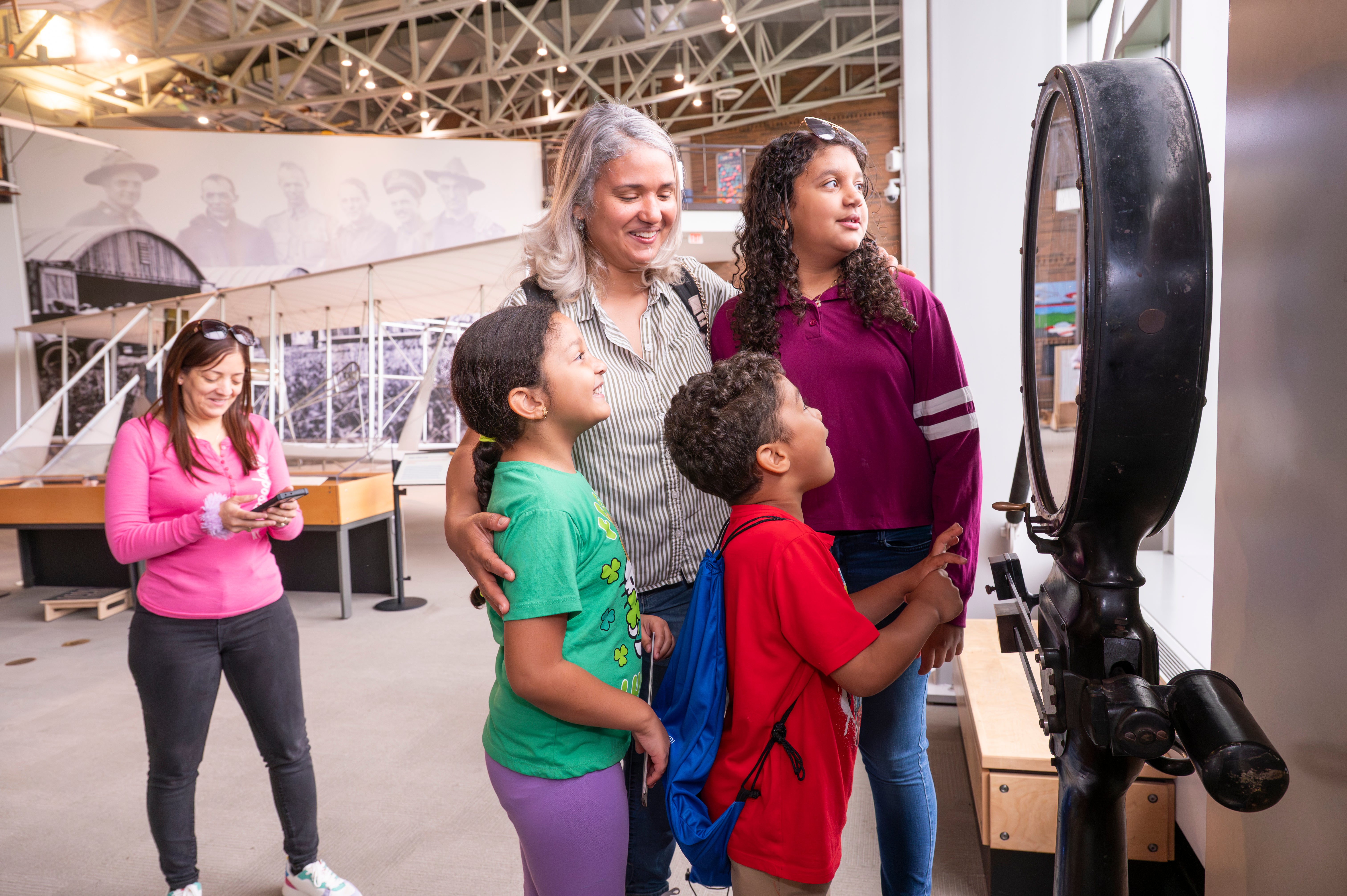 Family and children explore an interactive exhibit inside an aviation museum.
